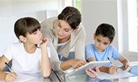 A parent helps two children with their studies